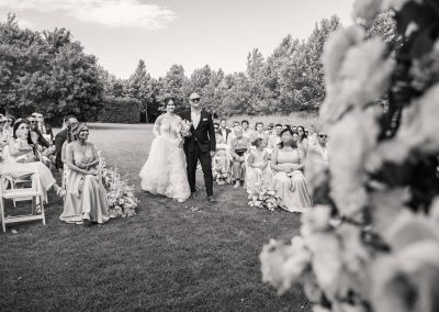 Esküvői kép a szertartásról, menyasszony és vőlegény kéz a kézben.