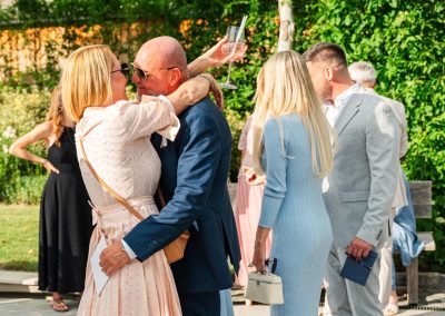Esküvői vendégek ölelik egymást a szabadban, boldog pillanat.