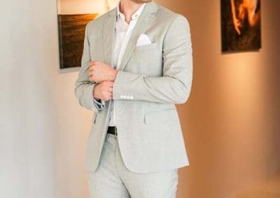Elegáns menyasszonyi öltönyben álló férfi esküvői képen.