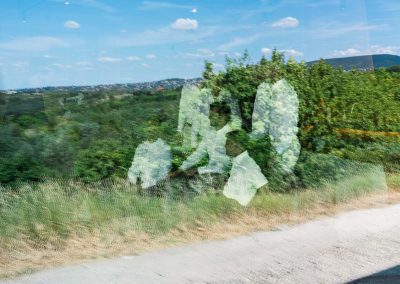 Terméskő szobor a természetben, vidéki táj háttérrel.