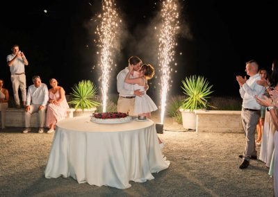 Esküvői pár csók a torta előtt, gyertyafényes ünnepi hangulatban.