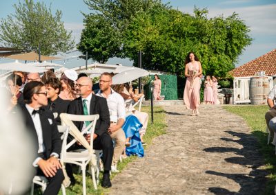 Esküvői vendégek a szabadban, napfényes kerthelyszínen.