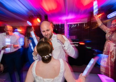 Esküvői pár első tánca a násznép előtt, színes fények és hangulat a táncparketten.