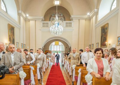 Esküvői ceremónia a klasszikus templomban, vendégek és pár a háttérben.