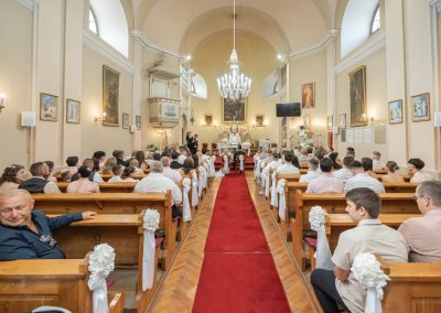 Esküvői szertartás a templomban, sok vendég jelenlétében.