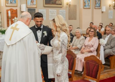 Esküvői ceremónia a templomban, jegyespár és pap az oltárnál.