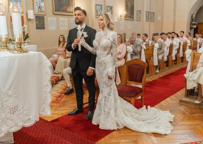 Esküvői szertartás a templomban, menyasszony és vőlegény az oltár előtt.