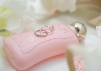 Rózsaszín esküvői parfüm és gyűrűk elegáns esküvői részletkép.