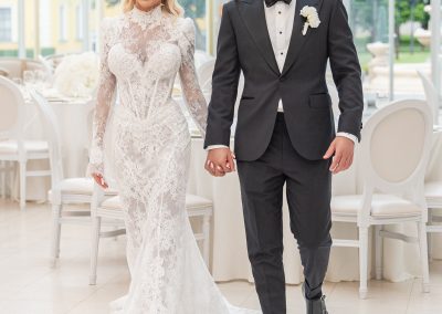 Esküvői pár kéz a kézben, elegáns menyasszony és vőlegény a szalonban.