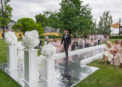 Esküvői ceremónia a szabadban, a vőlegény lép a színpadra.