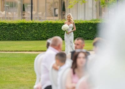 Esküvői kép menyasszonnyal a kertben, virágcsokorral.
