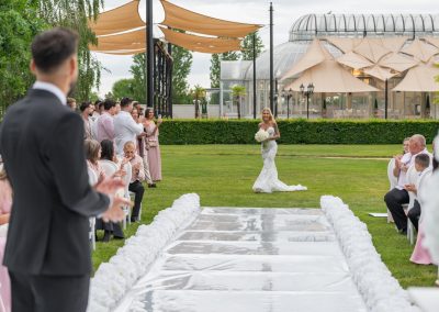 Esküvői ceremónia a szabadban, a menyasszony a vőlegény felé sétál.