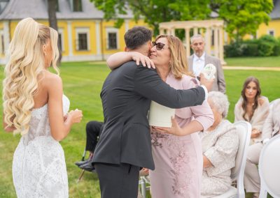 Fiatal pár öleli át az anyukát a szabadban.