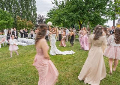 Esküvői vendégek táncolnak a szabadban, a menyasszony és a vőlegény a központban.