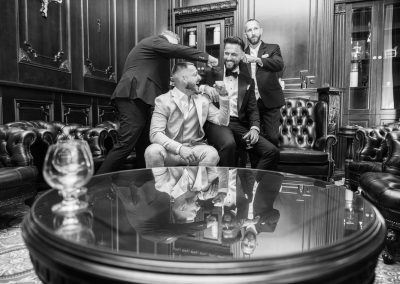 Baráti társaság barbershopban, elegáns öltözetben, jó hangulatban.