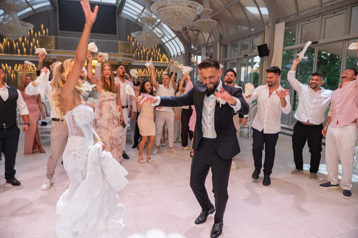 Lizi-es-David-eskuvoi-fotozas-Forgach-kastely- 447 Esküvői vendégek táncolnak egy elegáns helyszínen.