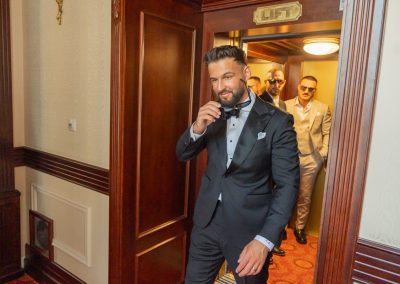 Elegáns vőlegény a menyasszonyi ceremónia előtt, stílusos öltönyben és nyakkendőben.
