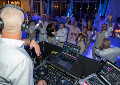 Esküvői buli a DJ pultnál, vendégek táncolnak és szórakoznak.